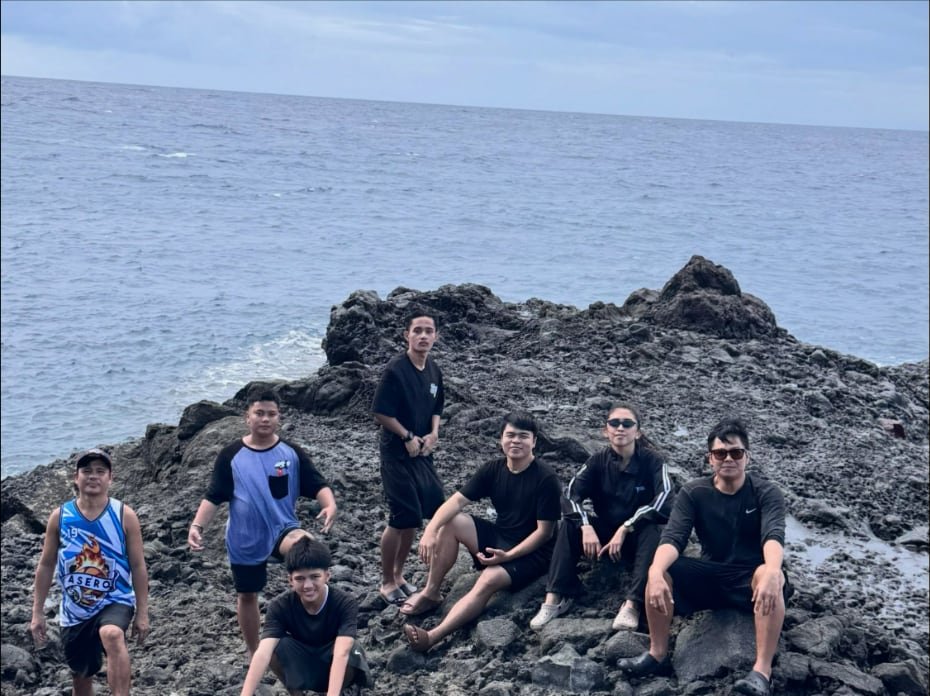 Grupo na nakaupo sa batuhan sa tabi ng dagat
