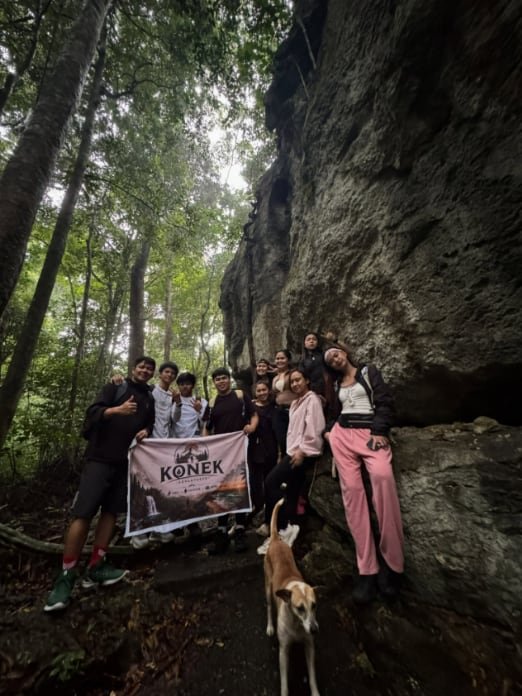 Grupo na may KONEK banner sa tabi ng limestone cliff, may kasamang aso